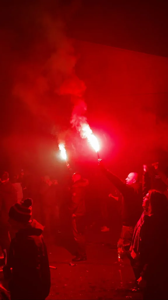 Hooligans-Hungria Hooligans Hungria de la Carpathian Brigade encendiendo bengalas rojas y generando una densa nube de humo en la noche de Budapest