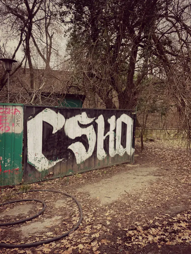 Graffiti CSKA letras góticas blancas en valla metálica oxidada parque Borisova Gradina
