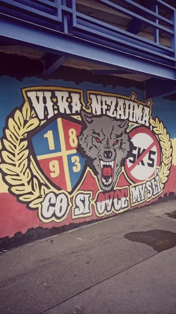 graffiti-ultras-sparta-praga Graffiti colorido de los ultras del Sparta Praga que muestra un lobo agresivo entre laureles, el año de fundación 1893 y un símbolo de prohibido sobre las siglas SKS (Slavia Praga), junto al lema en checo "Vlka nezajímá co si ovce myslí".