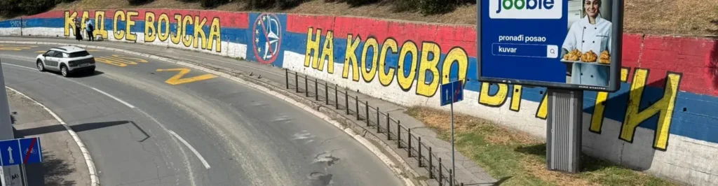 Mural nacionalista serbio en Belgrado con el lema "Cuando el ejército regrese a Kosovo" sobre bandera de Serbia y símbolo anti-OTAN.