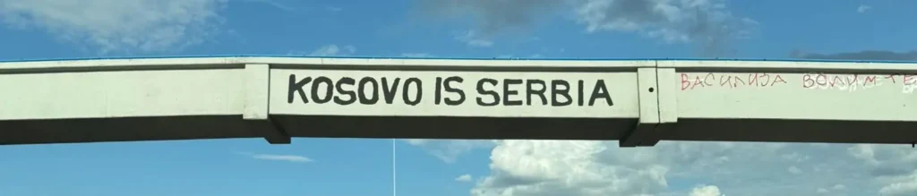 Pintada política en un puente de Belgrado con el lema "Kosovo is Serbia" en letras negras sobre hormigón, vinculada al nacionalismo de Delije Sever.